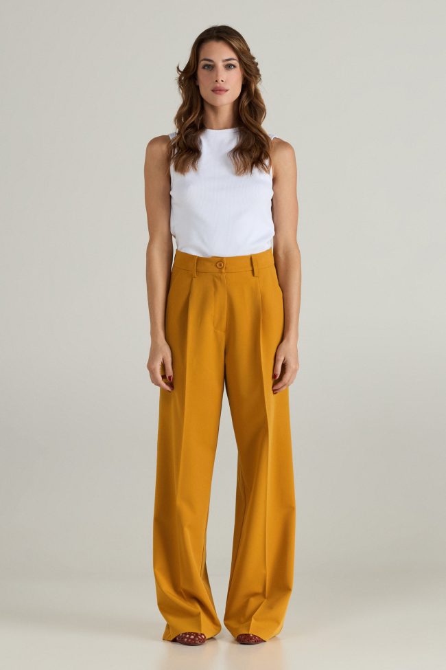 Model wearing mustard yellow oversized blazer with wide-leg trousers, styled with open sandals.