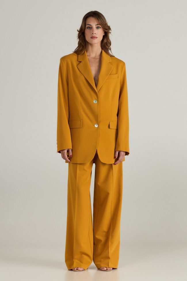 Model wearing mustard yellow oversized blazer with wide-leg trousers, styled with open sandals.