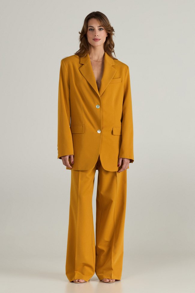 Model wearing mustard yellow wide-leg trousers, styled with open sandals.