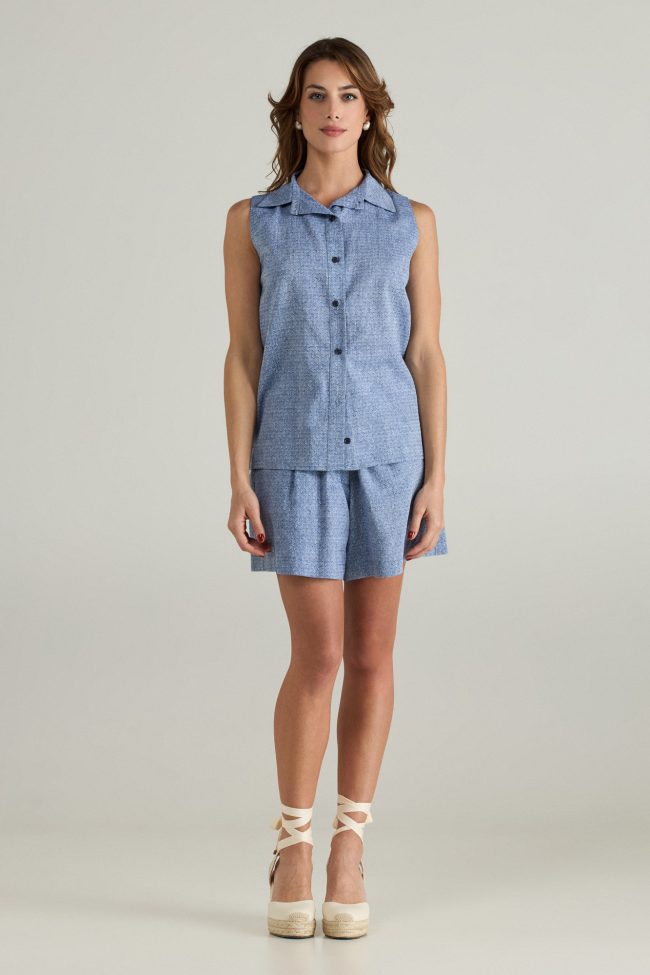Model wearinf sleeveless light blue shirt with pointed collar and front buttons paired with matching high-waisted shorts.