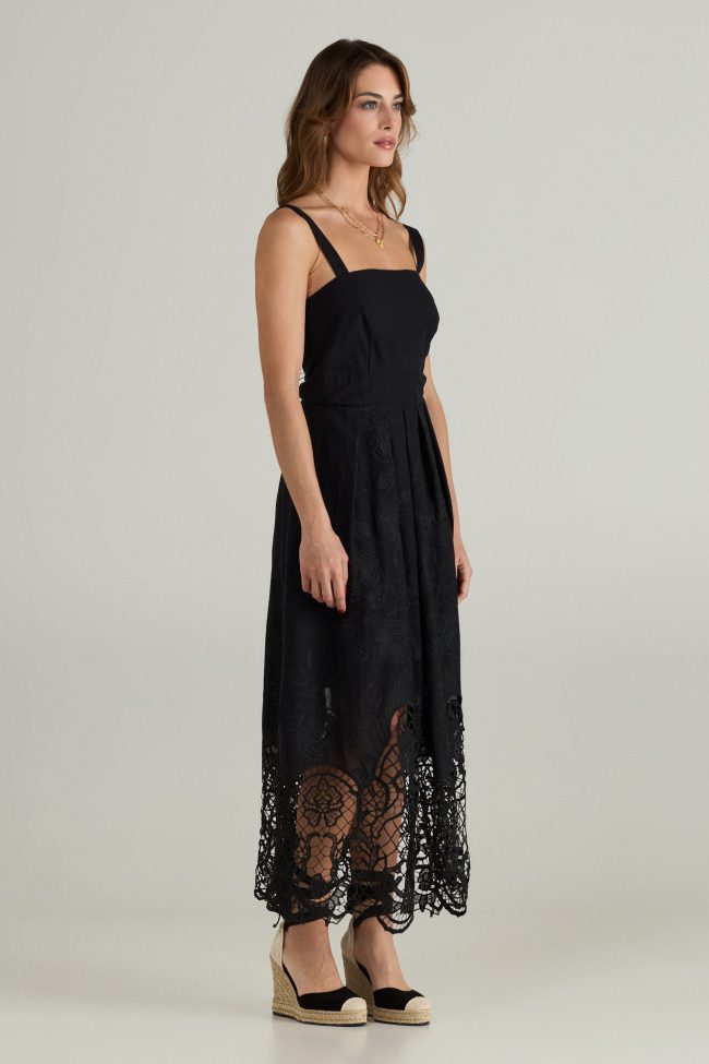 Model wearing black midi dress with wide straps, square neckline, and embroidered broderie anglaise hem.
