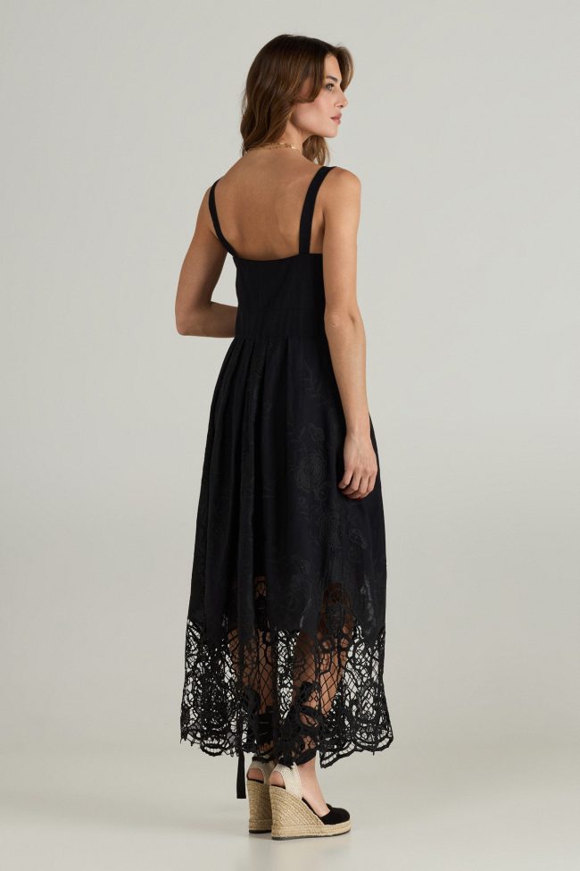 Model wearing black midi dress with wide straps, square neckline, and embroidered broderie anglaise hem.