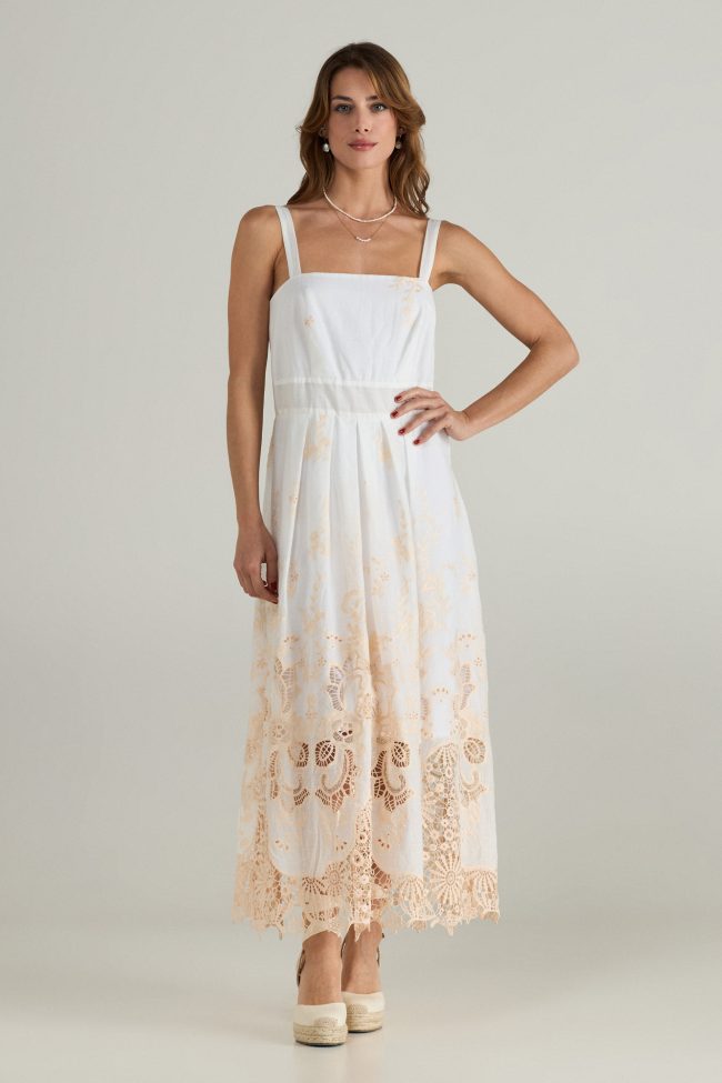 Model wearing a white sleeveless midi dress with beige broderie embroidery along the hem, wide straps and square neckline.