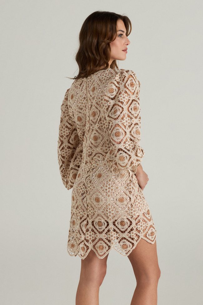 Model wearing a beige crochet mini dress with square neckline, balloon sleeves, and scalloped hemline.