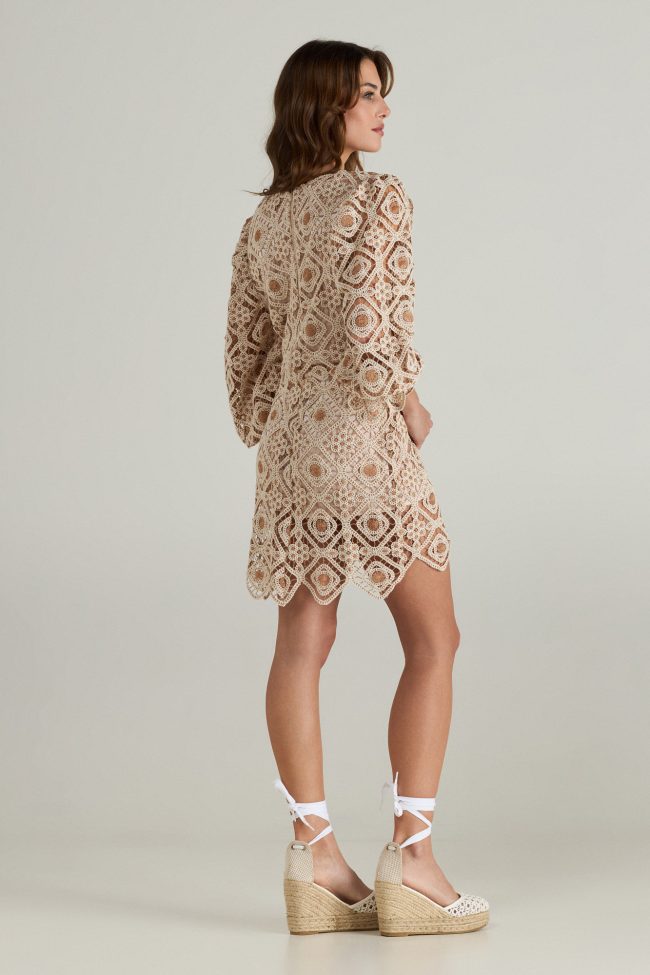 Model wearing a beige crochet mini dress with square neckline, balloon sleeves, and scalloped hemline.