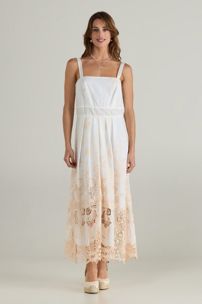 Model wearing a white sleeveless midi dress with beige broderie embroidery along the hem, wide straps and square neckline.