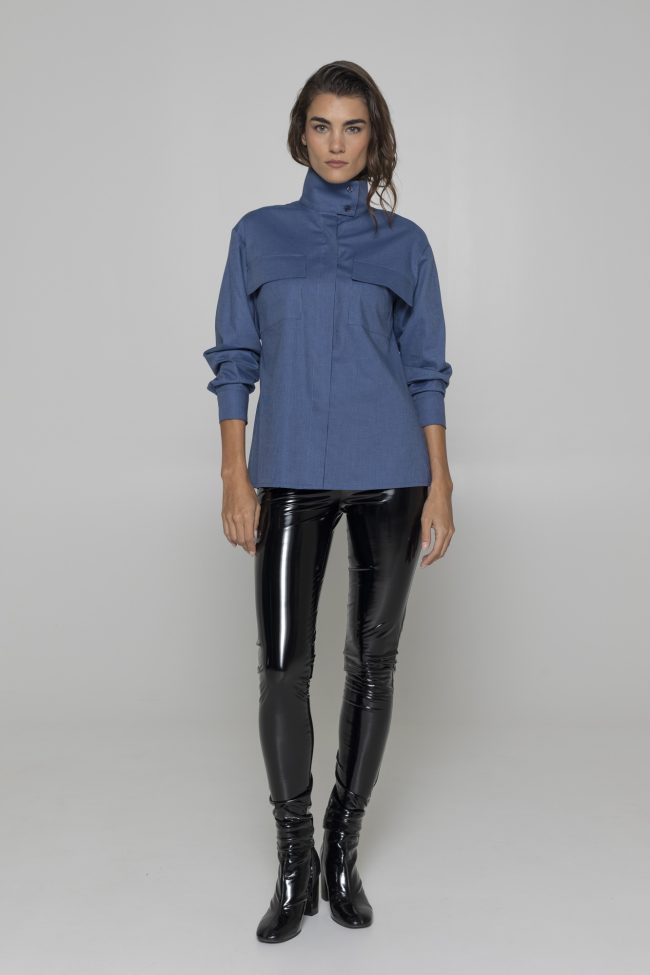 Model wearing a blue utility pocket shirt with glossy pants