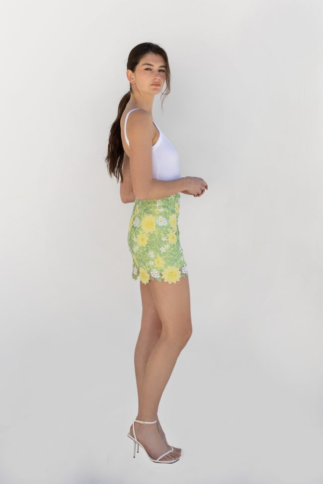 Green floral mini skirt with 3D flower appliqué, side view, styled with white tank top